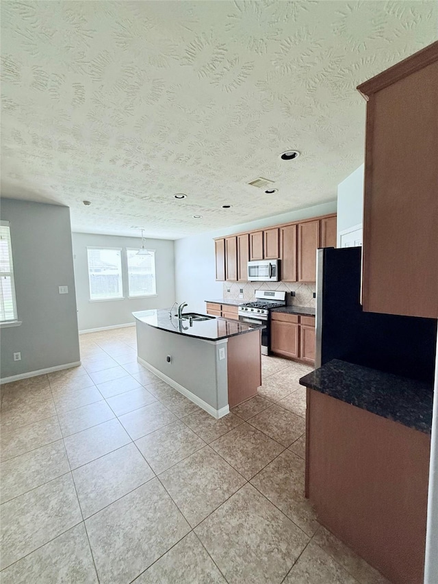 13938 Kenswick Key Ln, Houston, TX 77047 - kitchen with stainless steel appliances, dark countertops, a sink, a center island with sink, and light tile patterned floors