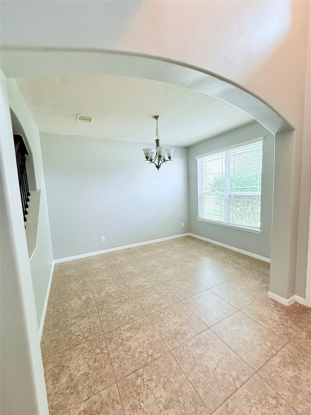 13938 Kenswick Key Ln, Houston, TX 77047 - empty room with light tile patterned floors, a chandelier, arched walkways, and baseboards