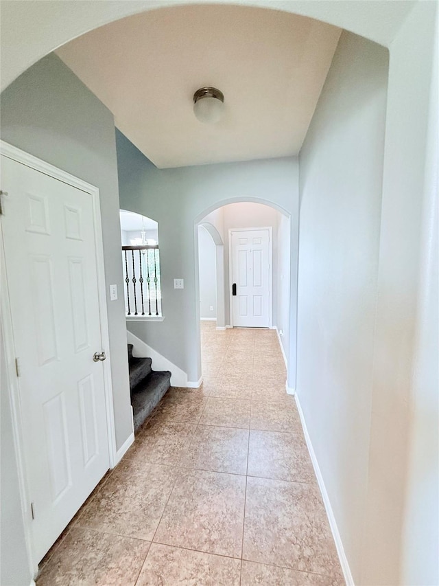 13938 Kenswick Key Ln, Houston, TX 77047 - hallway with arched walkways, stairway, baseboards, and light tile patterned floors