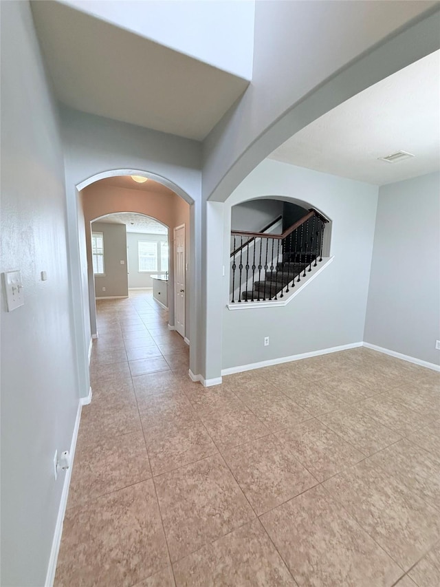 13938 Kenswick Key Ln, Houston, TX 77047 - corridor with arched walkways, light tile patterned floors, baseboards, and stairway
