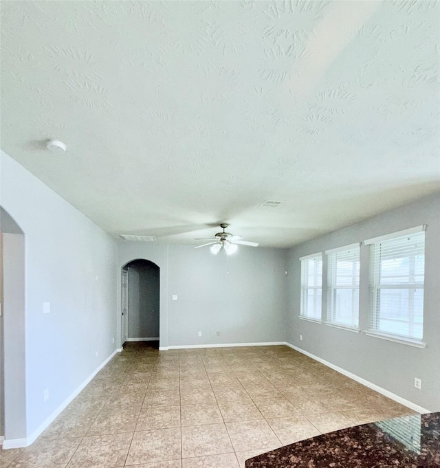 13938 Kenswick Key Ln, Houston, TX 77047 - empty room featuring arched walkways, a textured ceiling, a ceiling fan, light tile patterned floors, and baseboards