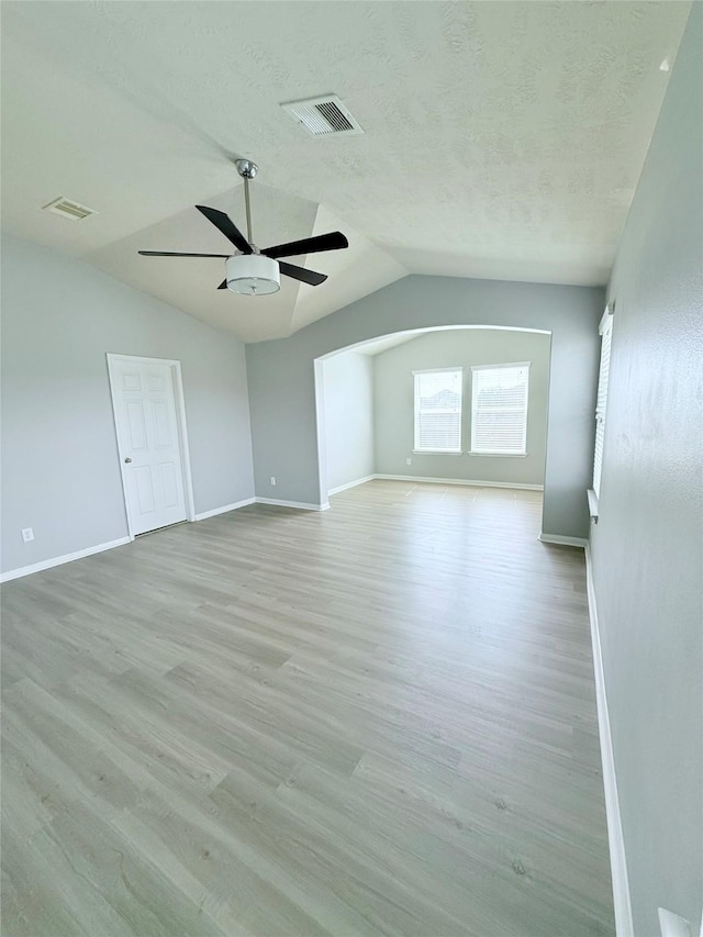 13938 Kenswick Key Ln, Houston, TX 77047 - unfurnished living room with vaulted ceiling, baseboards, ceiling fan, light wood-type flooring, and a textured ceiling
