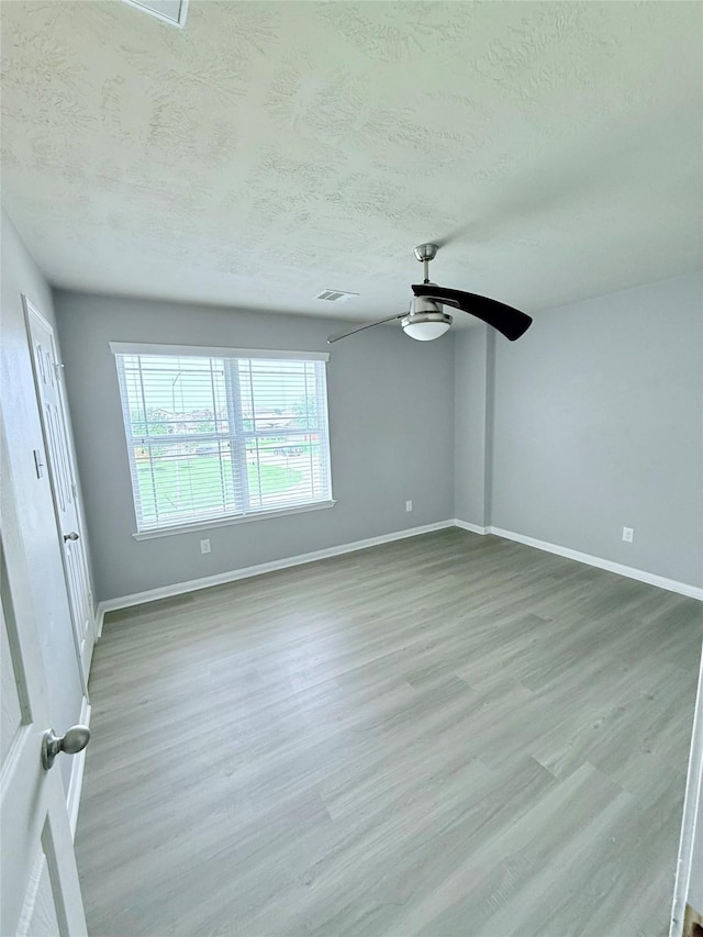 13938 Kenswick Key Ln, Houston, TX 77047 - empty room featuring a ceiling fan, baseboards, a textured ceiling, and light wood-type flooring