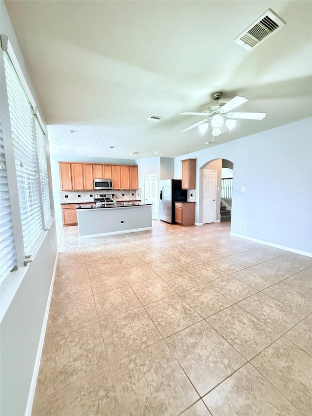 13938 Kenswick Key Ln, Houston, TX 77047 - unfurnished living room featuring arched walkways, a ceiling fan, baseboards, and light tile patterned flooring