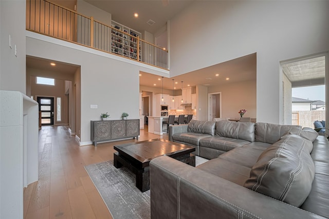 21714 Jenolan Ridge Rd, Cypress, TX 77433 - living area featuring a towering ceiling, healthy amount of natural light, light wood-type flooring, and baseboards