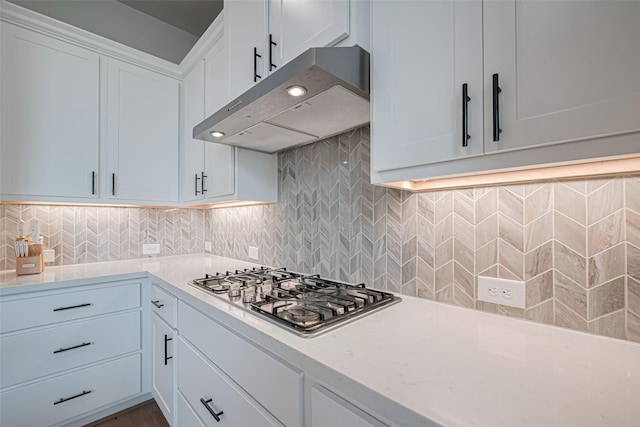 21714 Jenolan Ridge Rd, Cypress, TX 77433 - kitchen with under cabinet range hood, stainless steel gas stovetop, white cabinets, backsplash, and light stone countertops