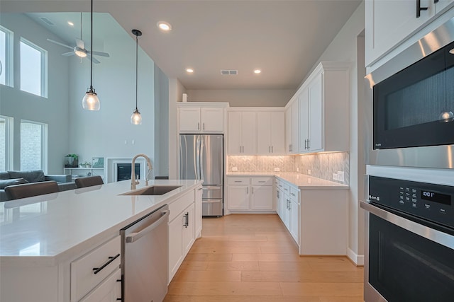 21714 Jenolan Ridge Rd, Cypress, TX 77433 - kitchen featuring appliances with stainless steel finishes, a sink, ceiling fan, tasteful backsplash, and a center island with sink