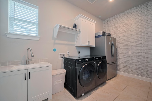 21714 Jenolan Ridge Rd, Cypress, TX 77433 - washroom featuring brick wall, cabinet space, washing machine and dryer, light tile patterned flooring, and baseboards