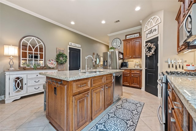 27438 Channing Springs Dr, Spring, TX 77386 - kitchen with appliances with stainless steel finishes, a sink, brown cabinetry, light tile patterned flooring, and a kitchen island with sink