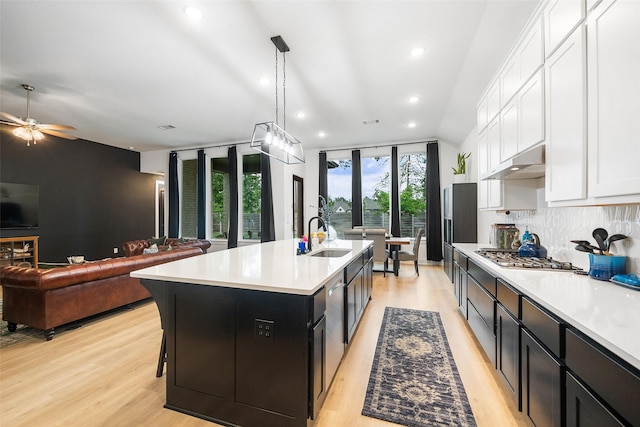 15040 Berry Brook Dr, Conroe, TX 77302 - kitchen with a sink, stainless steel gas cooktop, under cabinet range hood, light countertops, and white cabinetry