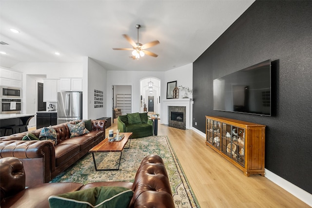 15040 Berry Brook Dr, Conroe, TX 77302 - living room featuring light wood finished floors, a ceiling fan, baseboards, a tile fireplace, and lofted ceiling