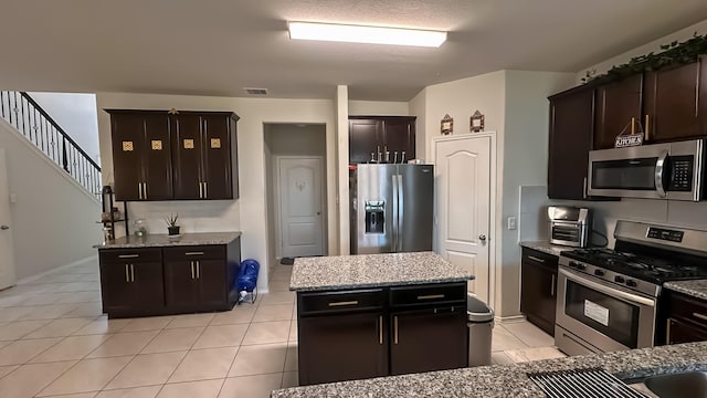 22614 Rosy Heights Trl, Tomball, TX 77377 - kitchen with appliances with stainless steel finishes, light tile patterned floors, light stone countertops, and a center island
