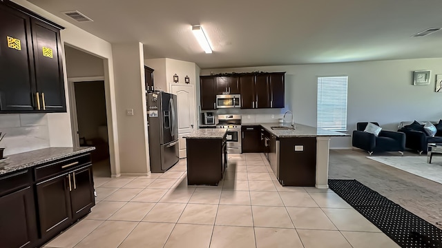 22614 Rosy Heights Trl, Tomball, TX 77377 - kitchen featuring appliances with stainless steel finishes, a sink, open floor plan, and light stone counters