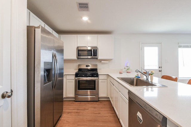 2728 Cadiz Bay Dr, Conroe, TX 77301 - kitchen with appliances with stainless steel finishes, a sink, light wood finished floors, light countertops, and white cabinets