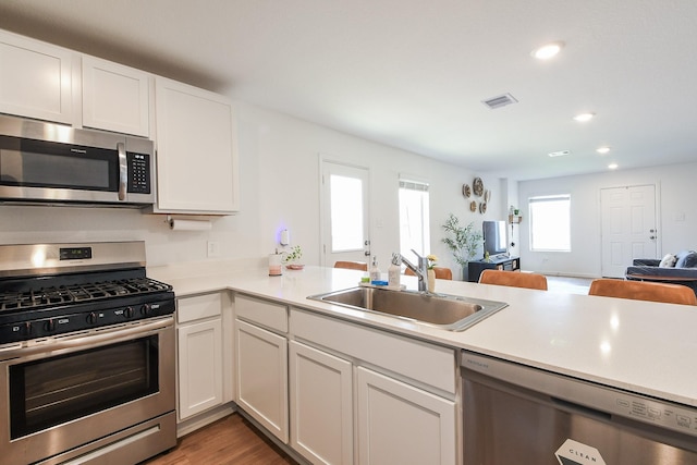 2728 Cadiz Bay Dr, Conroe, TX 77301 - kitchen featuring appliances with stainless steel finishes, a sink, open floor plan, light countertops, and recessed lighting