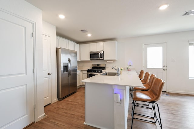 2728 Cadiz Bay Dr, Conroe, TX 77301 - kitchen with stainless steel appliances, a sink, a peninsula, a breakfast bar, and light wood finished floors