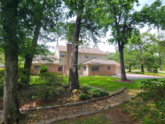456 Lexington Ct, Conroe, TX 77302 - rear view of property featuring a yard, an attached garage, concrete driveway, and brick siding