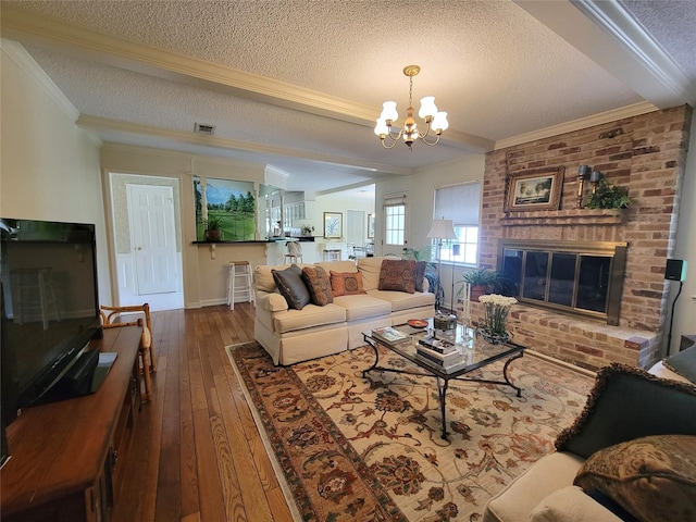 456 Lexington Ct, Conroe, TX 77302 - living area featuring a textured ceiling, wood-type flooring, ornamental molding, a chandelier, and a brick fireplace