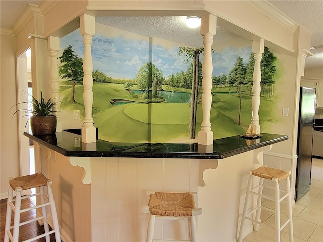 456 Lexington Ct, Conroe, TX 77302 - kitchen with a textured ceiling, light tile patterned flooring, crown molding, a kitchen breakfast bar, and dark countertops