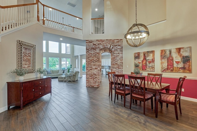 11872 Seashell Cir, Montgomery, TX 77356 - dining area featuring a chandelier, a towering ceiling, arched walkways, dark wood-style flooring, and baseboards