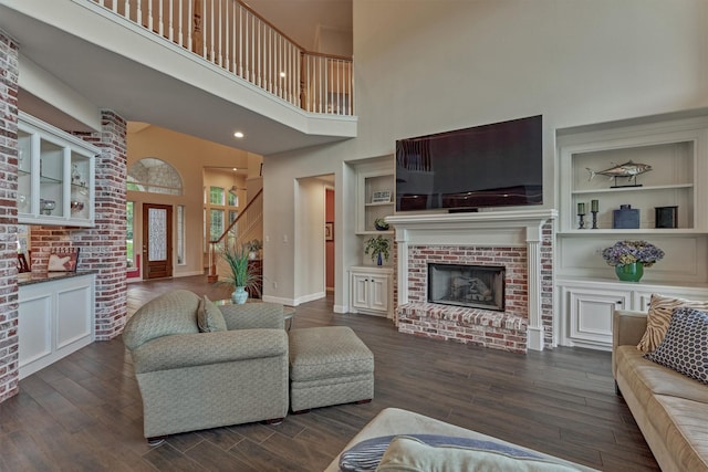 11872 Seashell Cir, Montgomery, TX 77356 - living area with a towering ceiling, a brick fireplace, dark wood-style floors, built in features, and baseboards