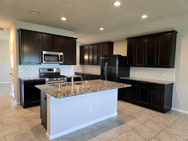 18411 Pelham Hollow Trl, Richmond, TX 77407 - kitchen with appliances with stainless steel finishes, stone countertops, tasteful backsplash, a center island with sink, and light tile patterned floors