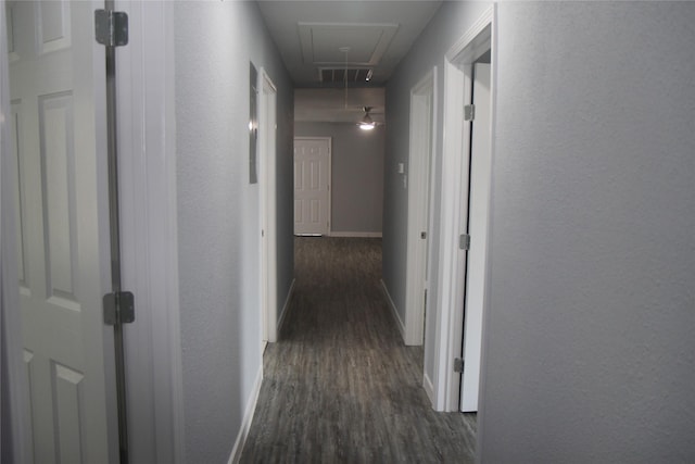 corridor with attic access, dark wood-type flooring, baseboards, and a textured wall