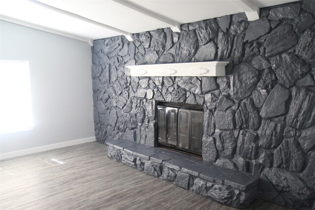 detailed view of a fireplace, beam ceiling, wood finished floors, and baseboards