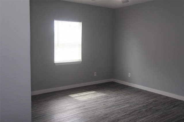 spare room featuring dark wood-type flooring, a ceiling fan, and baseboards