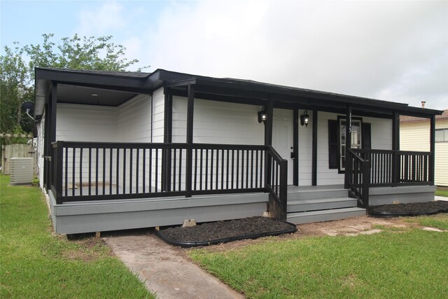 view of front of house with covered porch, central air condition unit, and a front yard