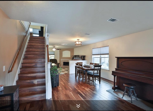 dining room with plenty of natural light, stairs, wood finished floors, and a ceiling fan