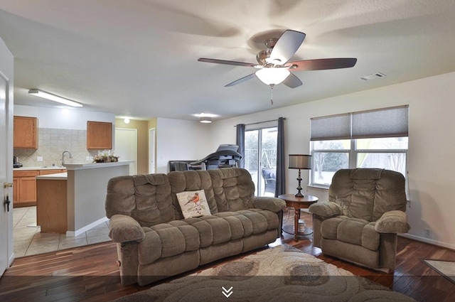 living room with light wood-type flooring, a ceiling fan, and baseboards