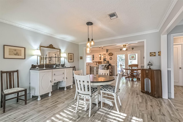 2607 E Pebble Beach Dr, Missouri City, TX 77459 - dining room with crown molding, light wood-style flooring, a ceiling fan, and a textured ceiling