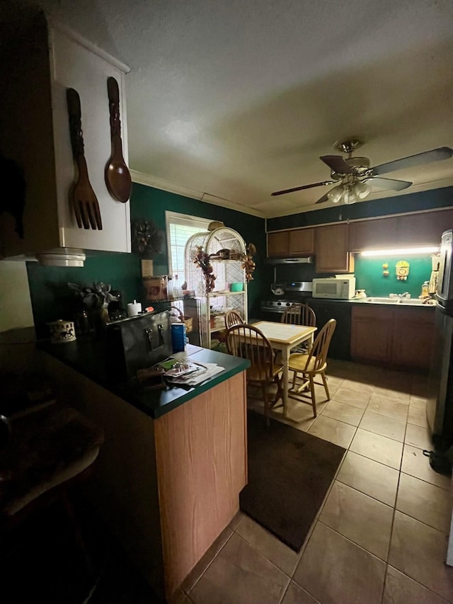 2923 Ellington St, Houston, TX 77088 - kitchen featuring a ceiling fan, under cabinet range hood, light tile patterned flooring, ornamental molding, and white microwave