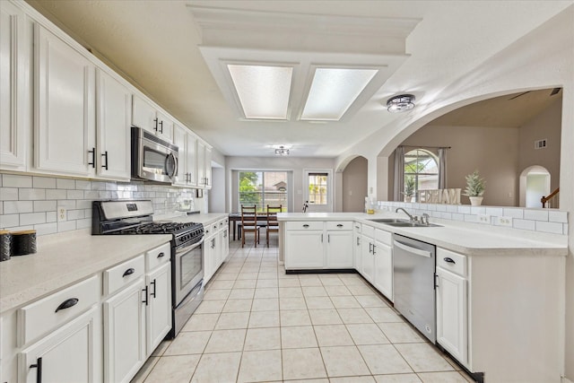 3413 Somerset Ln, Deer Park, TX 77536 - kitchen featuring stainless steel appliances, a sink, tasteful backsplash, arched walkways, and light countertops