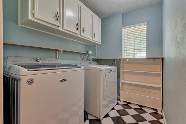 laundry area with tile patterned floors, washer and clothes dryer, cabinet space, and a textured ceiling