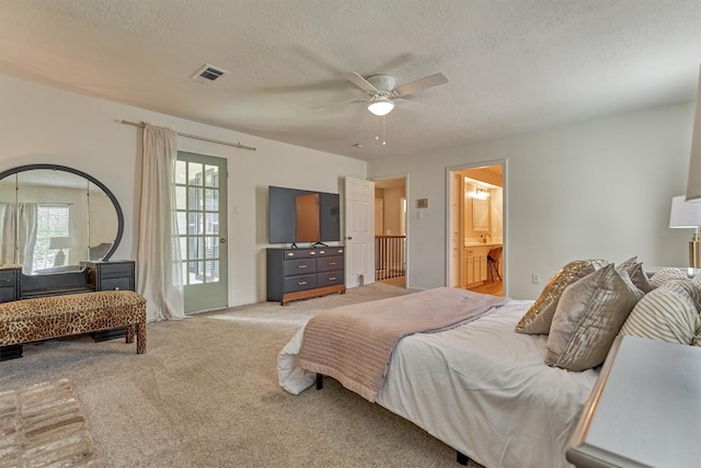 bedroom featuring light colored carpet, a textured ceiling, ceiling fan, and connected bathroom