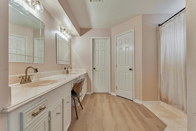 full bath with wood finished floors, double vanity, and baseboards