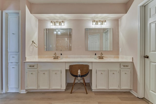 bathroom with wood finished floors, double vanity, and baseboards