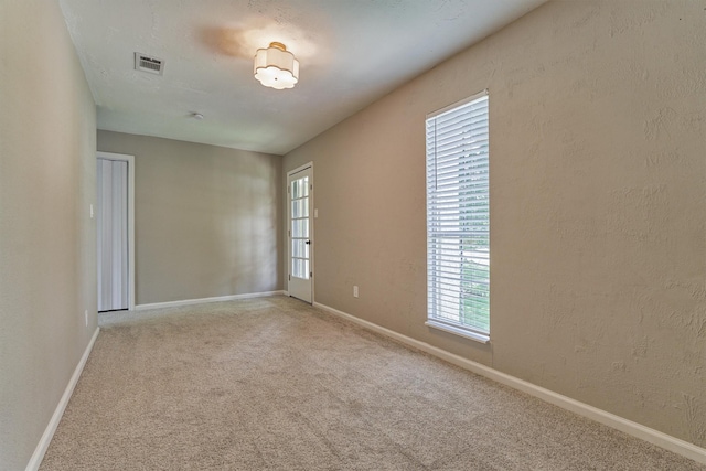 empty room featuring carpet, baseboards, and a textured wall