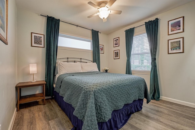 bedroom featuring wood finished floors, multiple windows, baseboards, and a ceiling fan