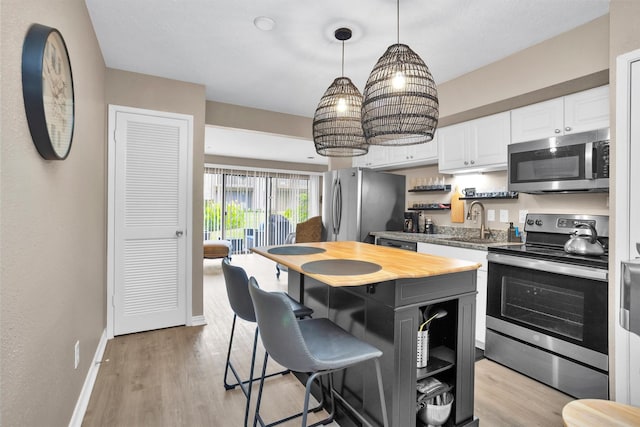 12900 Walden Rd Unit 715G, Montgomery, TX 77356 - kitchen with stainless steel appliances, open shelves, a kitchen bar, a sink, and white cabinetry