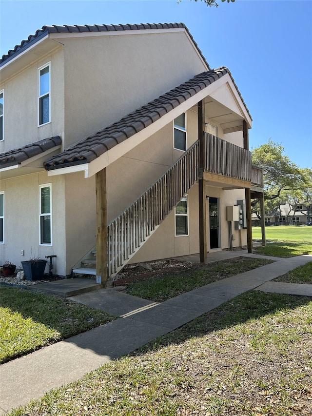 221 Marion Dr Unit 107C, Rockport, TX 78382 - view of home's exterior featuring a tiled roof, stucco siding, and a yard