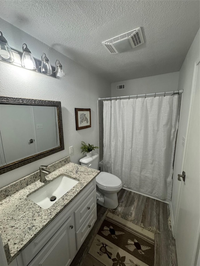 221 Marion Dr Unit 107C, Rockport, TX 78382 - bathroom with wood finished floors, a textured ceiling, vanity, toilet, and a shower with shower curtain