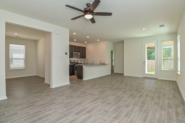 27638 Mesabe Dr, Magnolia, TX 77354 - unfurnished living room with ceiling fan, healthy amount of natural light, baseboards, light wood-type flooring, and recessed lighting