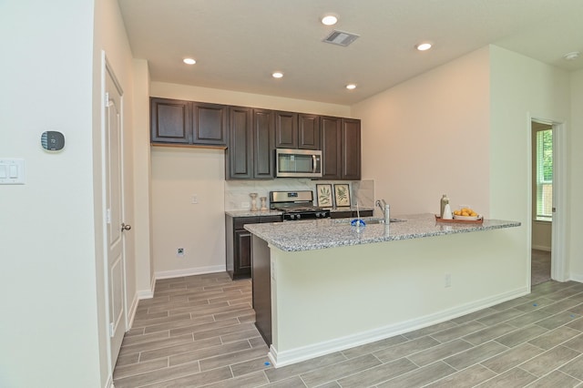 27638 Mesabe Dr, Magnolia, TX 77354 - kitchen with appliances with stainless steel finishes, a sink, light wood-type flooring, dark brown cabinetry, and baseboards