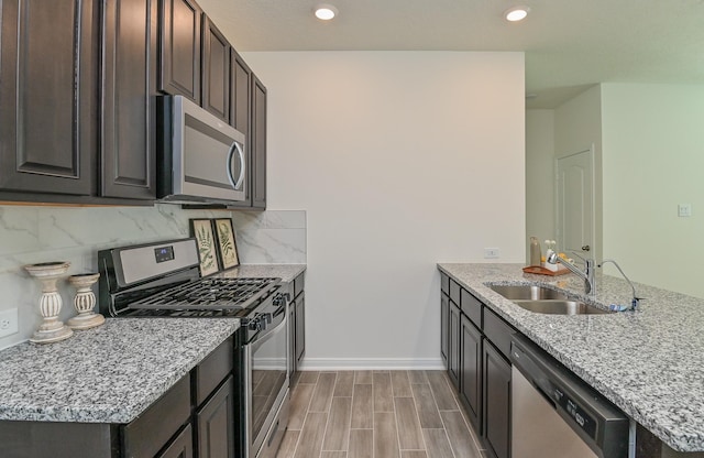 27638 Mesabe Dr, Magnolia, TX 77354 - kitchen featuring appliances with stainless steel finishes, a sink, a peninsula, dark brown cabinetry, and tasteful backsplash