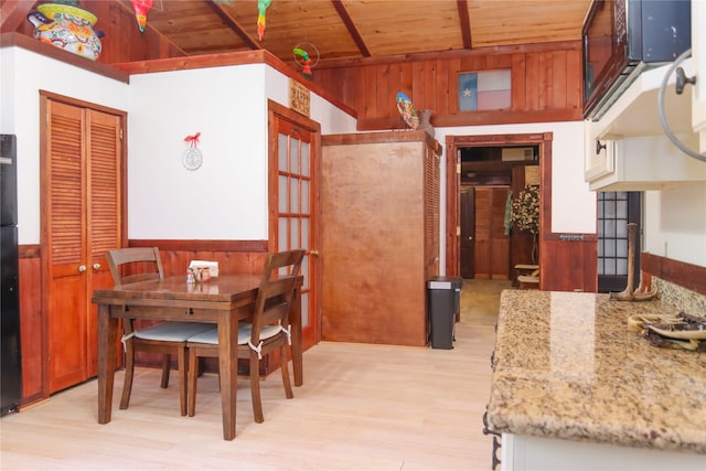 302 Bluebonnet Rd, Sheridan, TX 78950 - dining space featuring wood ceiling, wooden walls, light wood-style floors, a wainscoted wall, and lofted ceiling