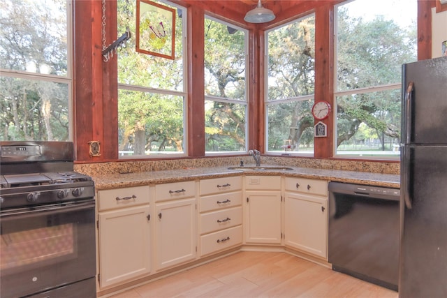 302 Bluebonnet Rd, Sheridan, TX 78950 - kitchen with black appliances, a sink, light wood-type flooring, light stone counters, and white cabinetry