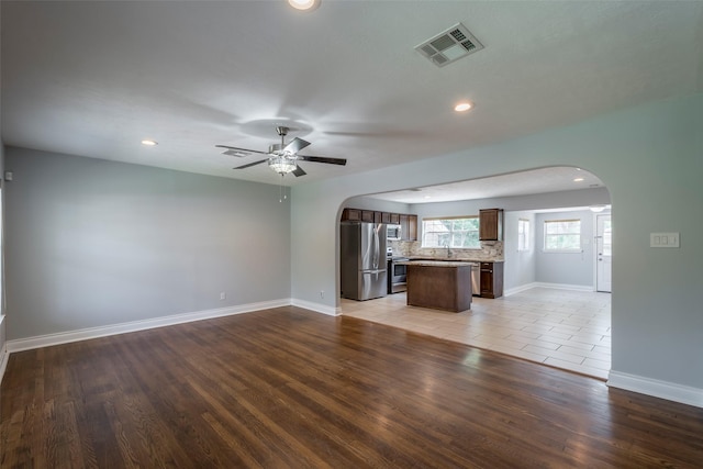 1109 Dismuke St, Houston, TX 77023 - unfurnished living room with arched walkways, a ceiling fan, baseboards, recessed lighting, and light wood-style floors